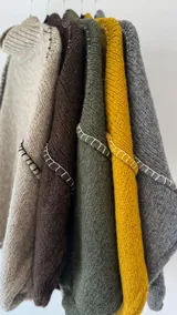 Buzo de punto oversize color chocolate, con cuello alto, mangas largas abullonadas y detalles de costuras bordadas a mano en color blanco en las uniones de las mangas.