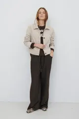 Buzo de tejido de punto en color beige, con cuello redondo y mangas largas. Presenta un delicado bordado de ramas y hojas en color crema en la parte superior del frente.