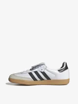 Zapatillas Adidas Samba LT blancas con las tres tiras negras y suela de goma color caramelo.
