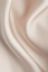 Pollera midi de tiro alto, color beige claro, con acabado satinado y caída suave. Presenta un elástico oculto en la cintura y un leve vuelo en el bajo.