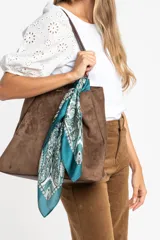 Pañuelo tipo bandana de forma cuadrada con estampado geométrico y floral en tonos verde petróleo, blanco y negro. Presenta bordes definidos y un acabado suave y ligero.