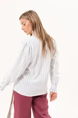 Camisa de manga larga con diseño a rayas celestes y blancas, cuello alto y detalle de volados en la cartera frontal y los puños.