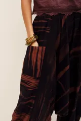 Pantalón babucha de algodón con estampa batik en tonos marrones y negros, tiro bajo y diseño amplio con puños elastizados en los tobillos.