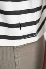 Remera de corte oversize confeccionada en algodón lavado, con diseño de rayas horizontales en color negro sobre fondo crudo, cuello redondo y mangas cortas.