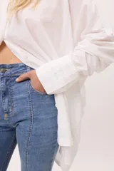 Camisa blanca oversize de algodón con cuello clásico, mangas largas y puños abotonados con detalle de tablas.