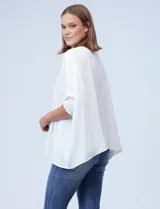 Blusa de crepe color blanco, con corte oversize, cuello redondo y mangas tipo dolman con puños elásticos en punto smock.