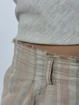 Pantalón largo de lino a rayas verticales en tonos beige, rosa y gris, con cintura alta y corte recto.