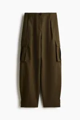 Pantalón cargo de sarga color verde militar, con tiro alto, cierre frontal con botón y corte holgado en las piernas estilo barrel. Cuenta con bolsillos laterales, bolsillos de fuelle con solapa en los muslos y trabillas abotonadas en los tobillos.