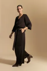 Pantalón ancho de tiro alto color marrón oscuro, con pinzas en la cintura, cinto incorporado y silueta fluida.