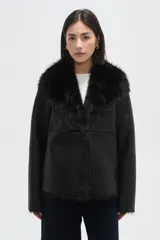 Chaqueta de eco-cuero negro con interior y cuello de piel sintética, diseño holgado, manga larga y cierre frontal con un botón.