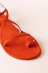 Sandalias planas color naranja de tiras finas, con suela plana y puntera descubierta.