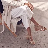 Sandalias de cuero color marrón, con taco ancho, diseño de tiras cruzadas y hebilla metálica de ajuste en el tobillo.