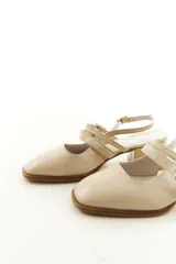 Zapatos tipo Mary Jane de charol color negro, con taco bloque, talón descubierto y doble tira frontal con hebillas metálicas.