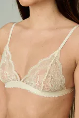 Conjunto de lencería de encaje color champagne, compuesto por un soutiene triangular de tirantes finos y una bombacha tipo colaless con tiras laterales regulables.
