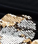 Remera de algodón color negro, con cuello redondo y mangas cortas. Presenta una estampa central en forma de corazón realizada con lentejuelas reversibles en tonos dorados y plateados.