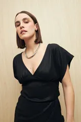 Top negro de tejido acanalado con acabado brillante, escote en V profundo, manga corta y frunce bajo el busto.