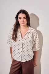 Blusa de lino y viscosa color blanco con estampado de lunares marrones, de manga corta y cuello camisero con cierre frontal de botones.