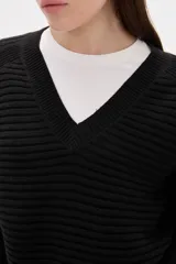 Sweater de punto color blanco, con cuello en V, manga larga y diseño holgado.