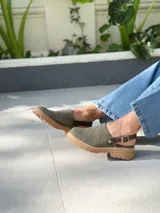 Zuecos de cuero color verde seco, con hebilla lateral y suela de goma.