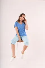 Pijama de dos piezas color coral, compuesto por una remera de manga corta con botones y un pantalón capri estampado con flores.