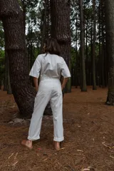 Mono blanco de gabardina de algodón, corte clásico con cierre frontal, pantalón largo con bolsillos, manga corta y cintura fruncida en la espalda.