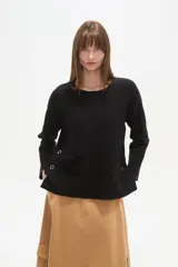Sweater negro liso, holgado, con cuello a la base y broches decorativos en el lateral.