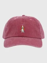 Gorra tipo baseball de algodón orgánico con efecto lavado, color rojo gastado. Presenta un bordado central pequeño de un perro Basset Hound y cierre posterior con hebilla metálica ajustable.