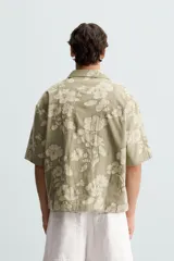 Camisa de manga corta y corte relajado confeccionada en tejido de algodón con diseño jacquard floral. Presenta cuello bowling, un bolsillo de plastrón en el pecho y cierre frontal con botones.