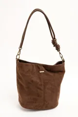 Cartera tipo bandolera de gamuza sintética color marrón, con asa larga decorada con nudos y detalles de herrajes metálicos dorados.