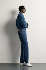 Jeans regular fit de tiro medio, confeccionados en denim de algodón azul oscuro con efecto lavado. Presenta diseño clásico de cinco bolsillos, pierna recta y cierre frontal con cremallera y botón.