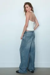 Jeans de tiro medio con diseño baggy barrel, cinco bolsillos y costuras laterales curvadas. Presenta cierre frontal con cremallera y botón metálico.