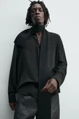 Camisa de corte relajado confeccionada en una mezcla de viscosa y algodón con textura. Presenta cuello solapa, cierre frontal de botones, manga larga con puños abotonados y aberturas laterales en el bajo.