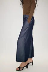 Pantalón culotte de tiro medio con pernera ancha y corta. Presenta nervios marcados en la parte delantera, bolsillos laterales y cierre frontal con cremallera, botón interior y hebilla ajustable en la cintura.