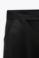 Pantalón cargo de tiro medio confeccionado en tejido satinado. Presenta bolsillos laterales tipo cargo, cierre frontal con cremallera y ganchos metálicos, y un cinturón integrado del mismo tejido con hebilla metálica.