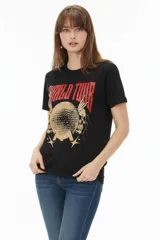Remera de algodón negra de manga corta y cuello redondo, con estampa frontal que incluye letras rojas y gráficos en tonos dorados.