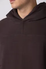 Buzo canguro de corte oversize en color gris con efecto lavado desgastado. Presenta diseño con recortes horizontales, capucha amplia y puños acanalados con etiqueta de marca en la manga.
