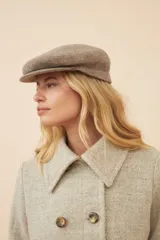 Boina con visera de lana fina uruguaya natural, sin teñir, con diseño de tejido texturizado en tonos beige y marrón.