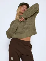 Sweater tejido de punto grueso con cuello alto, mangas largas raglán y puños acanalados. Presenta un diseño de calce holgado y textura acanalada.