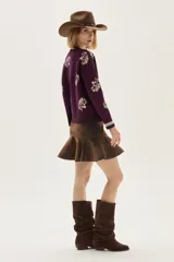 Sweater de punto color bordó con diseño de flores estampadas en tono crema, cuello redondo y puños con detalle de franjas en contraste. Presenta un bordado pequeño en el pecho.