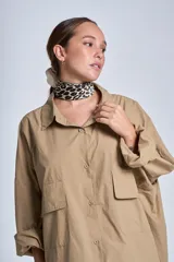 Camisa oversize color beige de manga larga con bolsillos frontales.