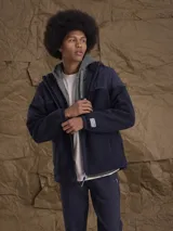 Campera con capucha confeccionada en una combinación de tejido técnico y sherpa, con cierre frontal completo y puños elásticos.