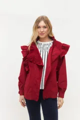 Campera de pana color blanco, de corte oversize, con cuello alto, cierre frontal de botones y volados decorativos en los hombros y cuello.