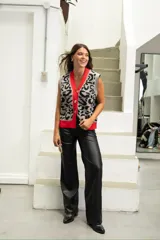 Chaleco de punto con diseño animal print en tonos gris y negro, con cuello en V y borde frontal en color rojo vibrante. Presenta cierre frontal con botones grandes y corte holgado.