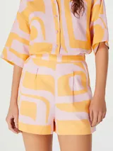 Short de tiro alto con diseño estampado en tonos naranja y rosado, con pinzas frontales y cierre lateral.