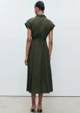 Vestido midi de corte evasé en color verde oliva, con cuello camisero, cierre frontal de botones y mangas cortas con dobladillo. Incluye un cinturón de la misma tela para ajustar a la cintura y detalle de pinzas delanteras.