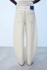 Jeans de tiro medio con cinco bolsillos, pernera holgada tipo barrel que se estrecha hacia el tobillo, y detalle de costuras a contraste. Cuenta con cierre frontal de cremallera y botón.