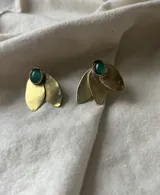 Par de caravanas doradas con forma de hojas y una piedra verde redonda en la parte superior.