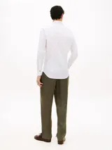 Camisa blanca de corte slim, confeccionada en sarga de mezcla de algodón elástico, con cuello italiano, mangas largas con puño y cierre frontal de botones.
