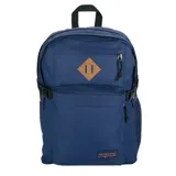 Mochila Jansport modelo Main Campus de color azul, confeccionada en tela resistente, con múltiples compartimentos, bolsillos laterales de red y parche de cuero sintético frontal.