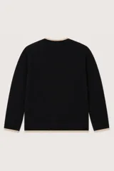 Saco de punto negro con diseño cruzado, cuello en V y ribetes en color beige. Presenta cierre frontal con botones claros, dos bolsillos delanteros aplicados y mangas largas.